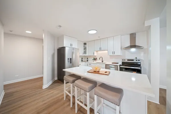 a kitchen with a refrigerator a stove a sink and a dining table with wooden floor