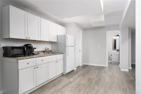 a kitchen with granite countertop white cabinets and refrigerator