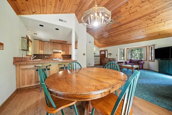 a dining room with furniture a kitchen a chandelier a wooden table and chairs