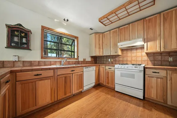 a kitchen with granite countertop white cabinets white stainless steel appliances a sink and a large window