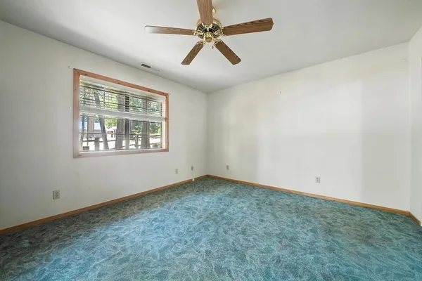 an empty room with windows and fan