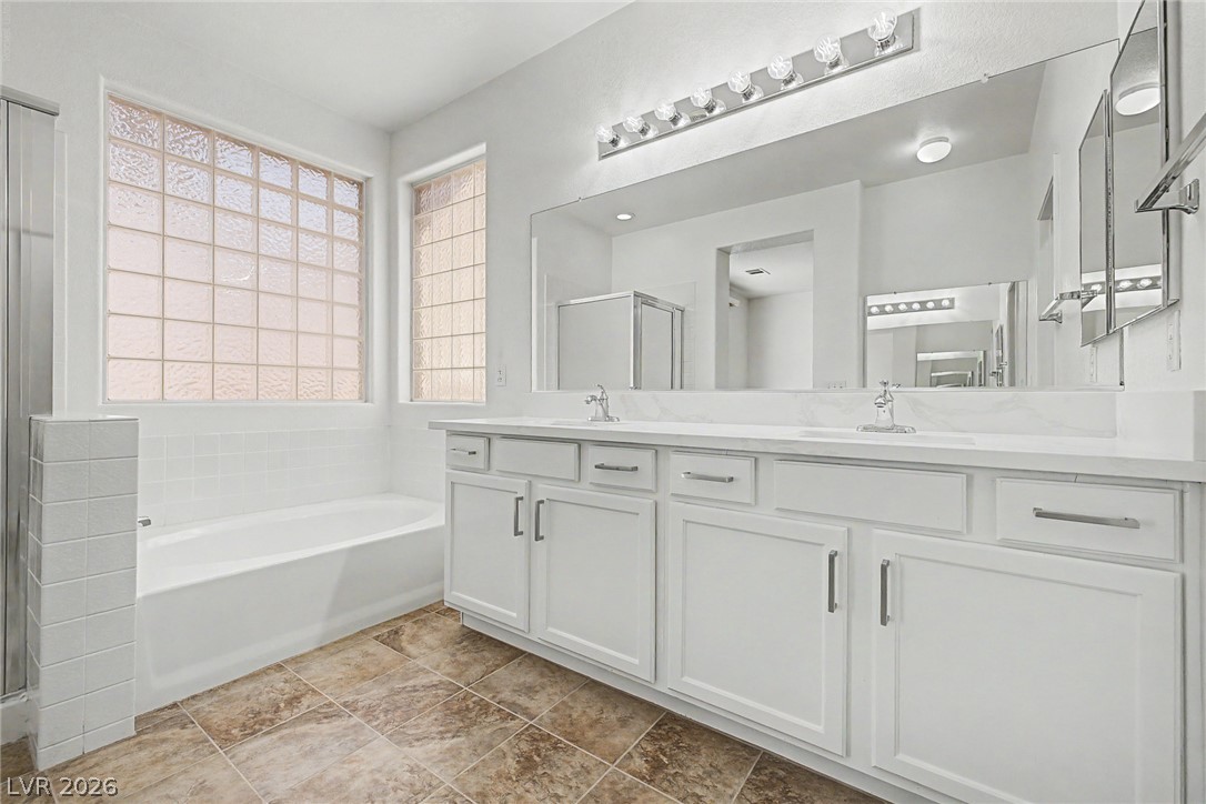 835 Entrada Ridge Avenue Henderson, NV 89012 - Photo 17 of 34 Dual vanities and a deep soaking tub provide ultimate relaxation in this well-appointed bathroom.
