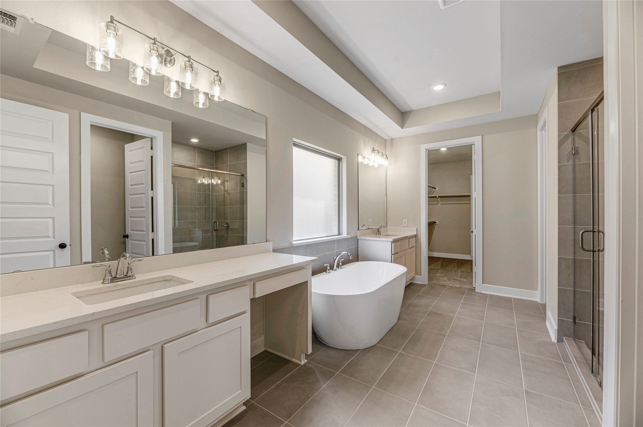 1508 Rodeo Ridge Drive Georgetown, TX 78628 - Photo 10 of 37 Full bathroom featuring two vanities, light tile patterned flooring, a shower stall, a freestanding tub, and a spacious closet