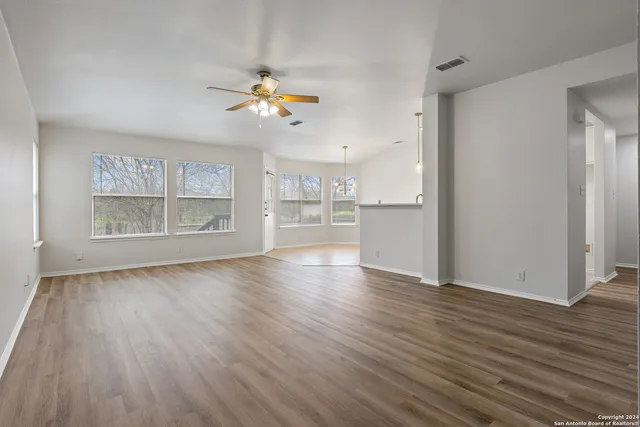 an empty room with wooden floor cabinet and windows