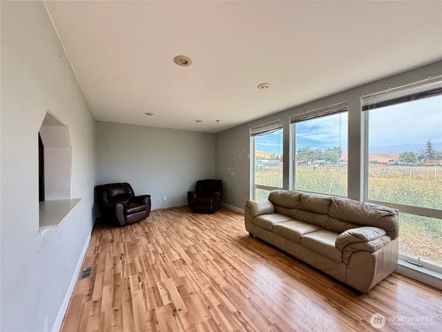 a view of an empty room with a window and a kitchen