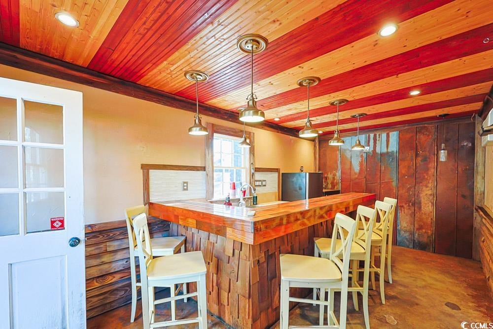 509 Beaty Street Conway, SC 29526 - Photo 28 of 40 Indoor dry bar with decorative light fixtures, butcher block countertops, freestanding refrigerator, recessed lighting, and wooden walls