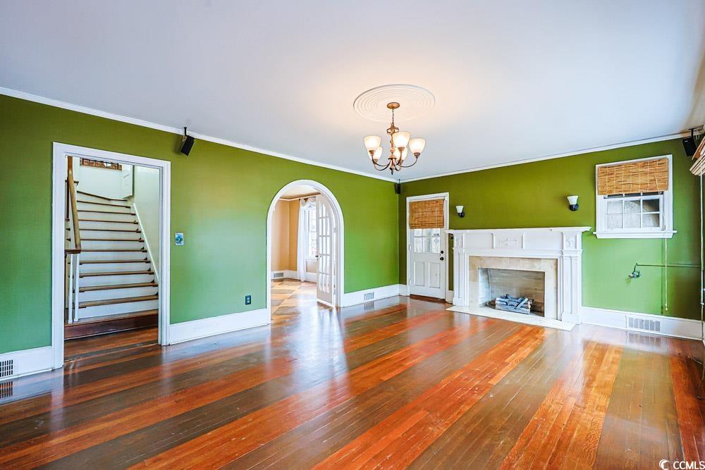 509 Beaty Street Conway, SC 29526 - Photo 3 of 40 Unfurnished living room featuring stairs, arched walkways, dark wood-style floors, crown molding, and a premium fireplace