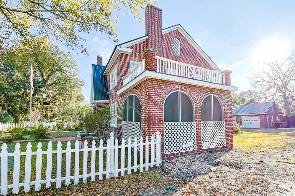 509 Beaty Street Conway, SC 29526 - Photo 39 of 40 Rear view of property featuring a chimney, a fenced front yard, brick siding, and a balcony