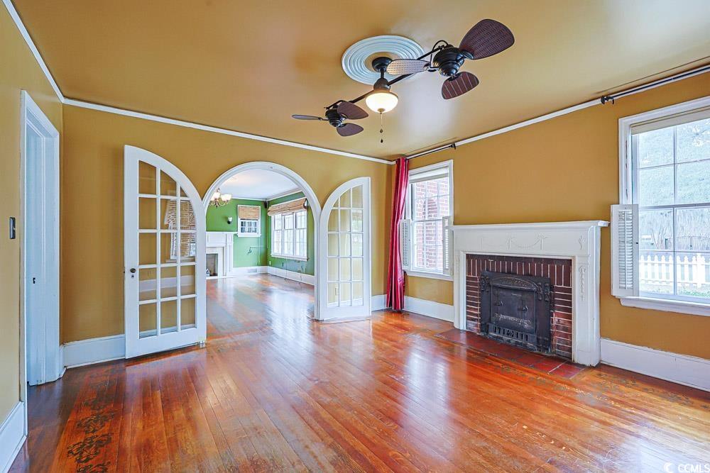 509 Beaty Street Conway, SC 29526 - Photo 6 of 40 Unfurnished living room featuring a brick fireplace, hardwood / wood-style floors, ornamental molding, ceiling fan, and french doors