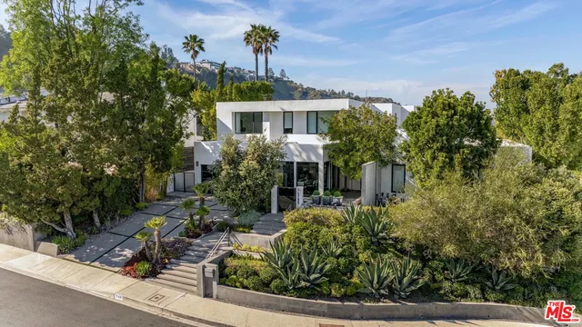 a front view of a house with a yard and potted plants