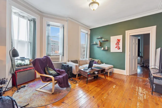 a living room with furniture a wooden floor and a large window