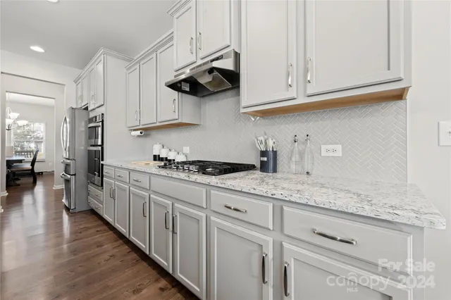 a kitchen with granite countertop cabinets stainless steel appliances and a wooden floor