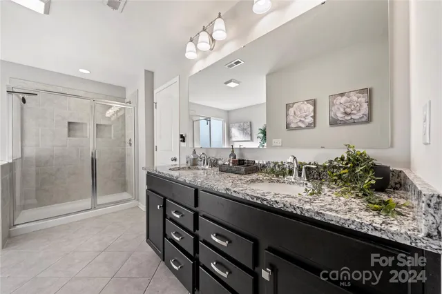 a spacious bathroom with a granite countertop sink a mirror and a shower