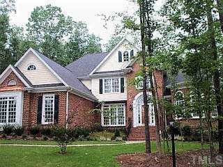 a front view of a house with a garden and trees