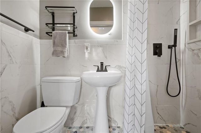 a bathroom with a toilet sink and shower curtain