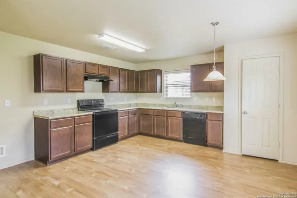 a large kitchen with a refrigerator stove a sink dishwasher and microwave with wooden floor