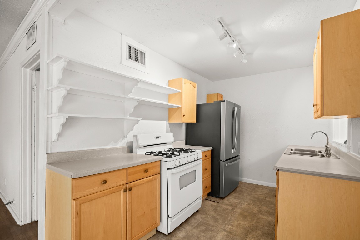 1707 Alguno Road, Unit C Austin, TX 78757 - Photo 14 of 16 Kitchen featuring light brown cabinetry, white gas stove, light countertops, rail lighting, and open shelves