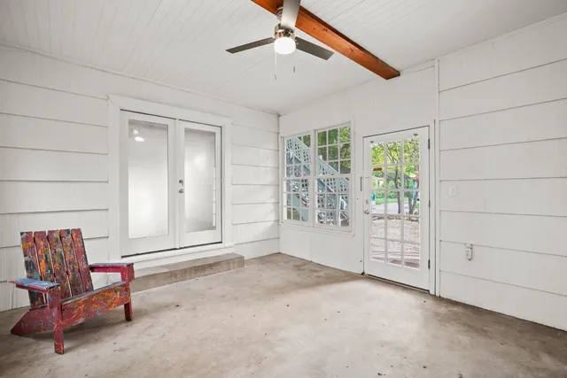 an empty room with wooden floor ceiling fan and windows