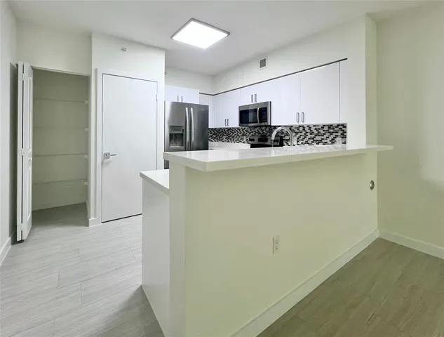 a view of kitchen with stainless steel appliances a refrigerator and a stove top oven