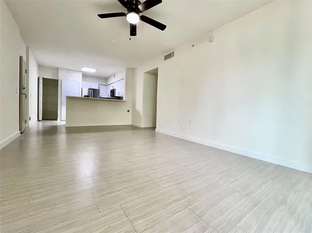 a view of a room with wooden floor a ceiling fan and windows