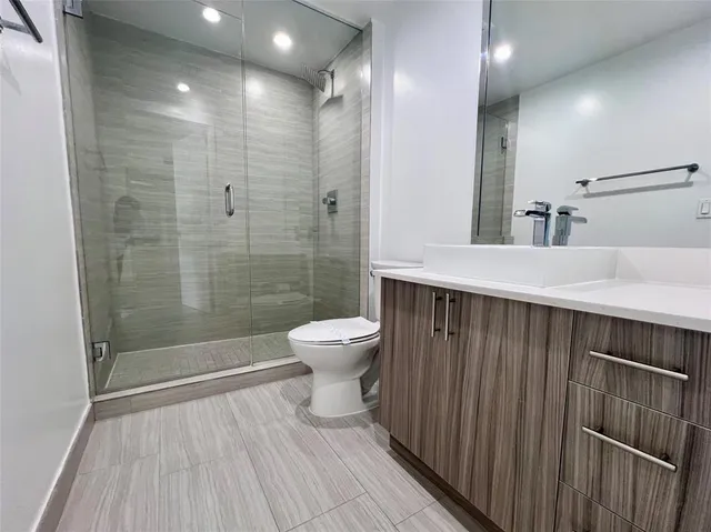 a bathroom with a sink a toilet a mirror and shower