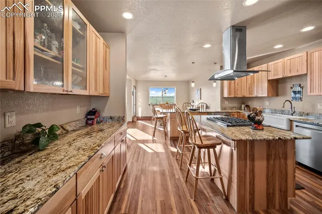 a kitchen with stainless steel appliances granite countertop a stove top oven a sink dishwasher and cabinets with wooden floor
