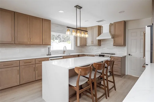 a kitchen with stainless steel appliances granite countertop white cabinets a sink and a stove