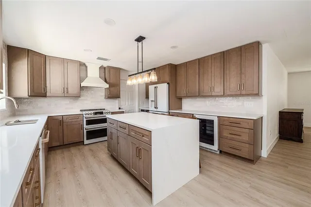 a kitchen with stainless steel appliances granite countertop a stove a sink dishwasher and a refrigerator with wooden floor