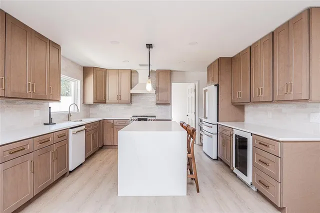 a kitchen with kitchen island wooden cabinets a sink a stove a refrigerator and island