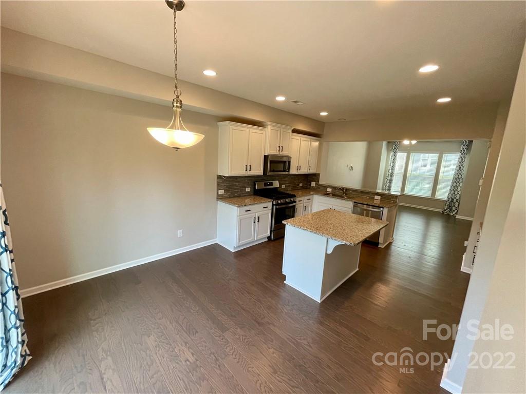 715 Swift Run Tega Cay, SC 29708 - Photo 6 of 24 a view of a kitchen with kitchen island granite countertop a stove top oven a sink a counter top space and cabinets