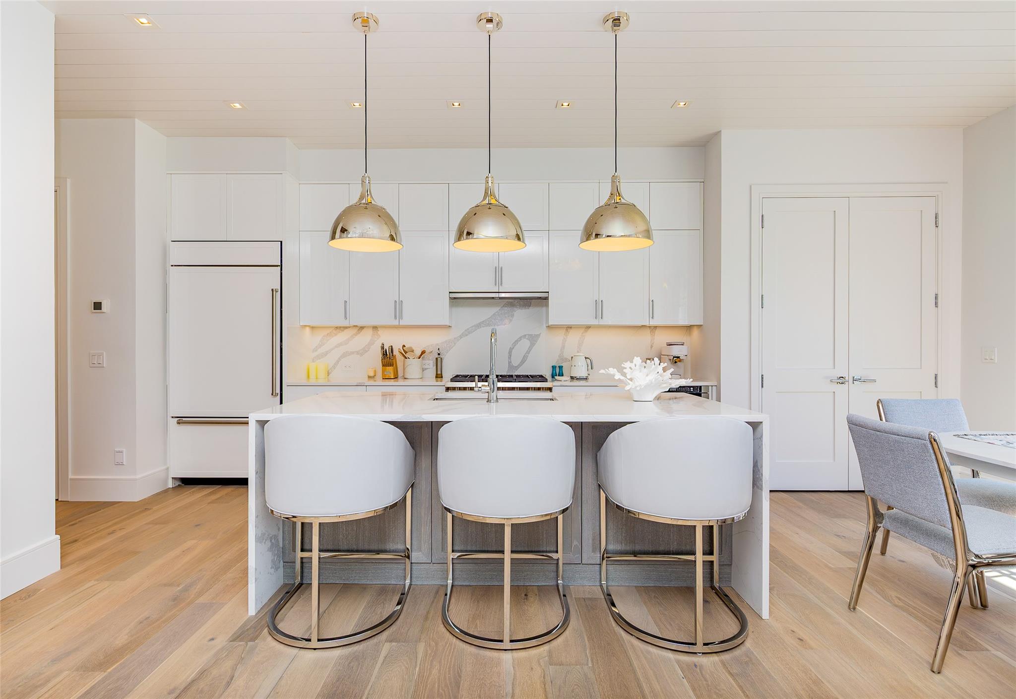 1 Spruce Court Water Mill, NY 11976 - Photo 9 of 35 Kitchen with light countertops, white cabinets, a kitchen island with sink, a kitchen bar, and paneled refrigerator