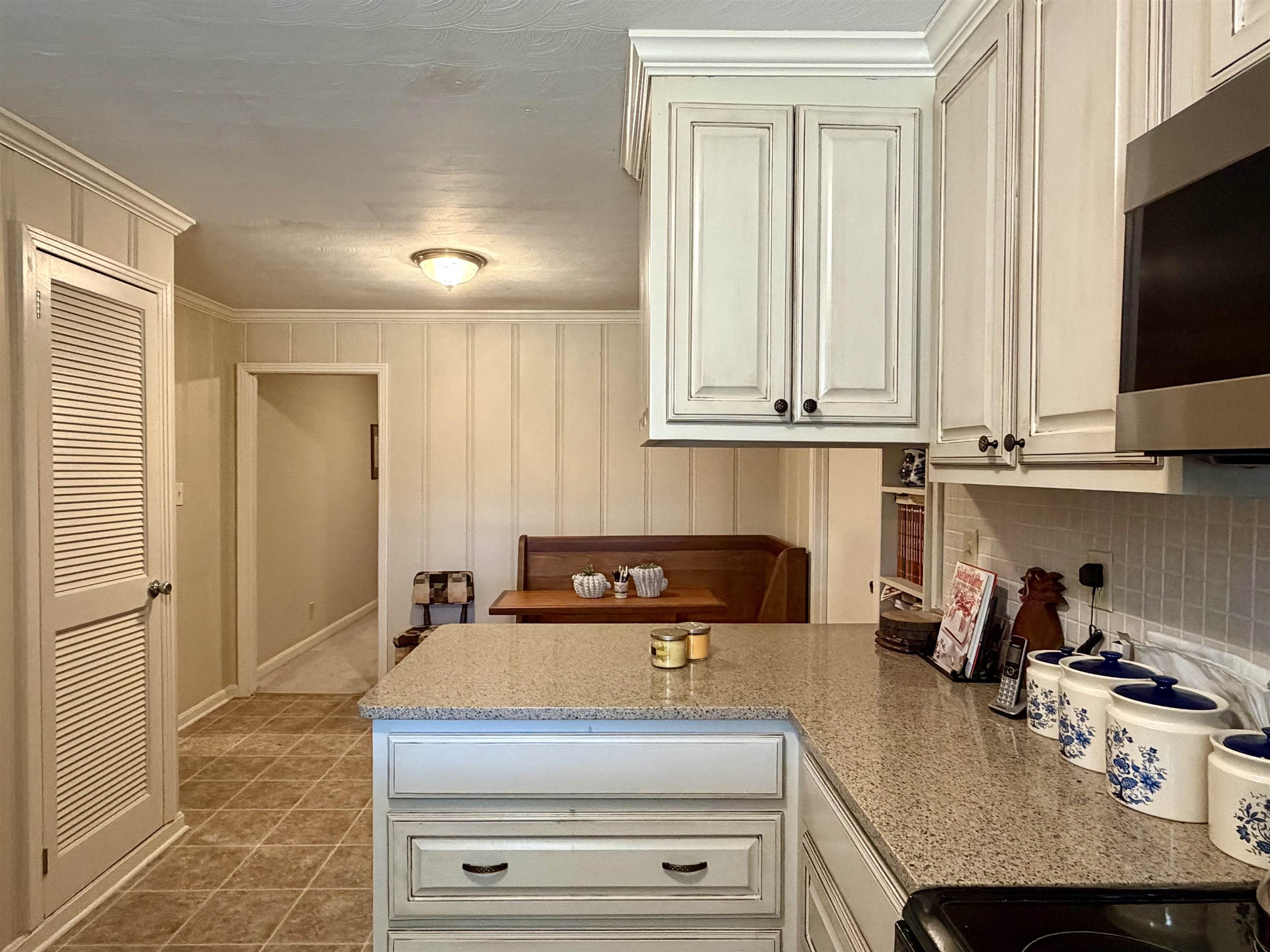 254 Michie Road Michie, TN 38357 - Photo 5 of 16 Kitchen with stainless steel microwave, crown molding, decorative backsplash, a peninsula, and light stone countertops