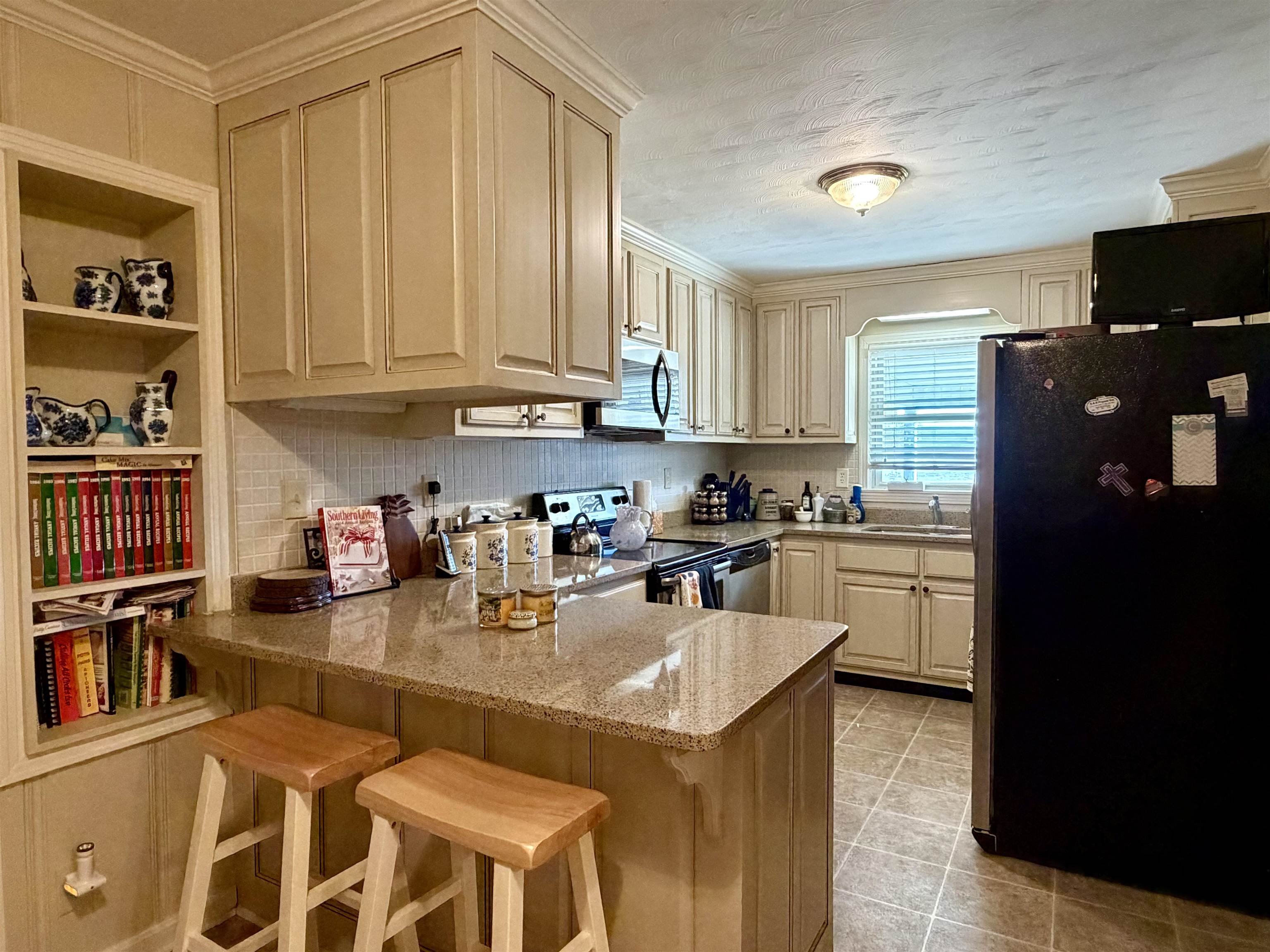 254 Michie Road Michie, TN 38357 - Photo 6 of 16 Kitchen with stainless steel appliances, a peninsula, a kitchen bar, light stone counters, and ornamental molding