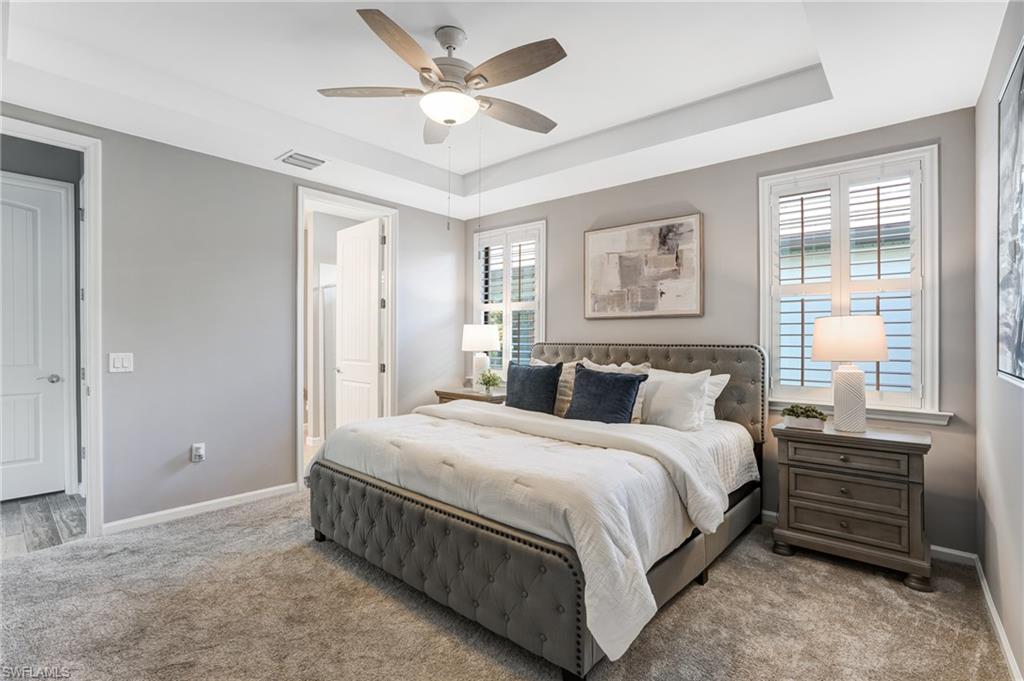 20308 Corkscrew Shores Boulevard Estero, FL 33928 - Photo 17 of 47 Carpeted bedroom featuring a tray ceiling, baseboards, connected bathroom, and ceiling fan