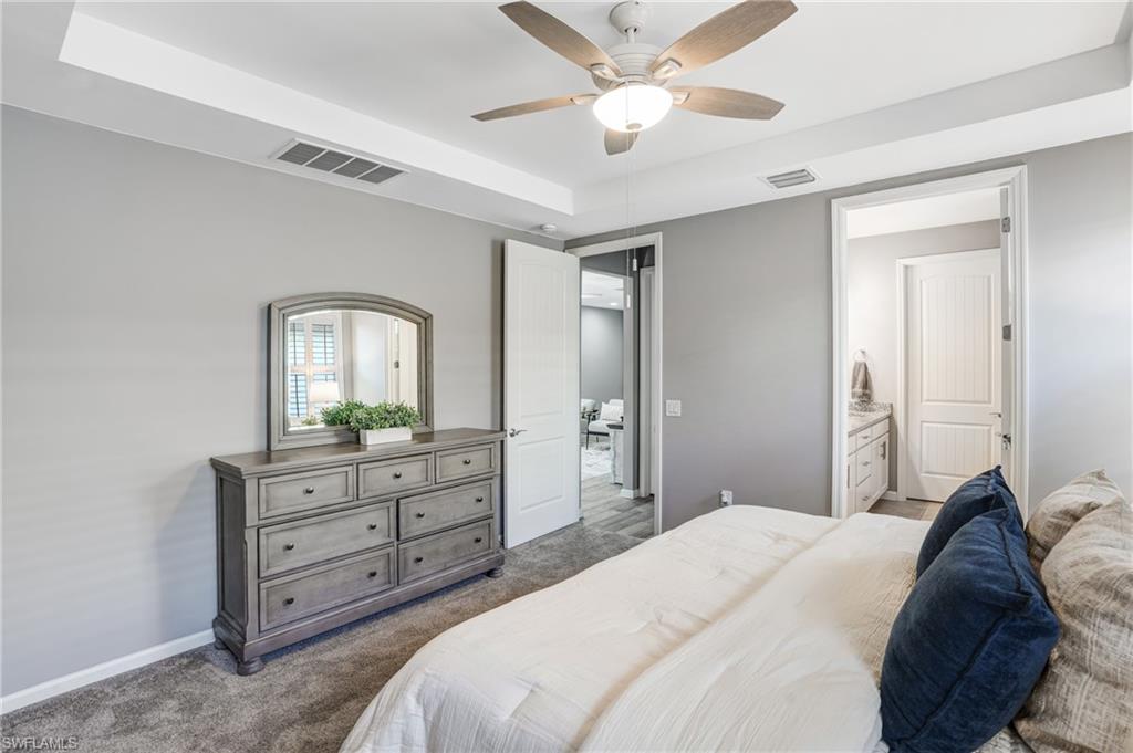 20308 Corkscrew Shores Boulevard Estero, FL 33928 - Photo 18 of 47 Bedroom featuring dark carpet, a raised ceiling, baseboards, ceiling fan, and connected bathroom