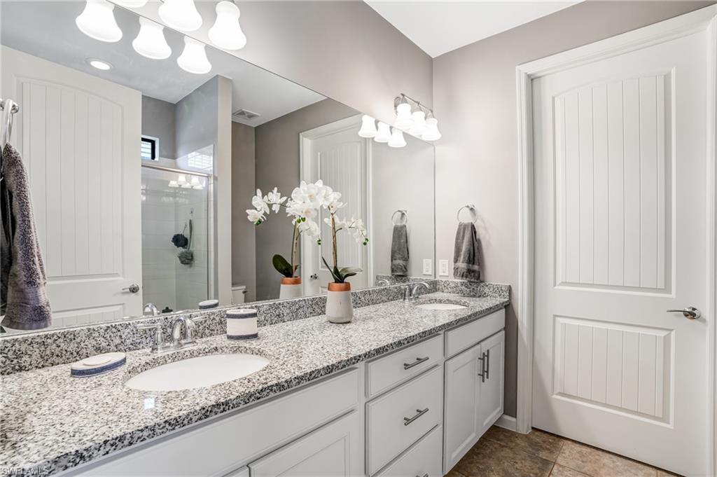20308 Corkscrew Shores Boulevard Estero, FL 33928 - Photo 19 of 47 Bathroom with double vanity, a stall shower, and toilet