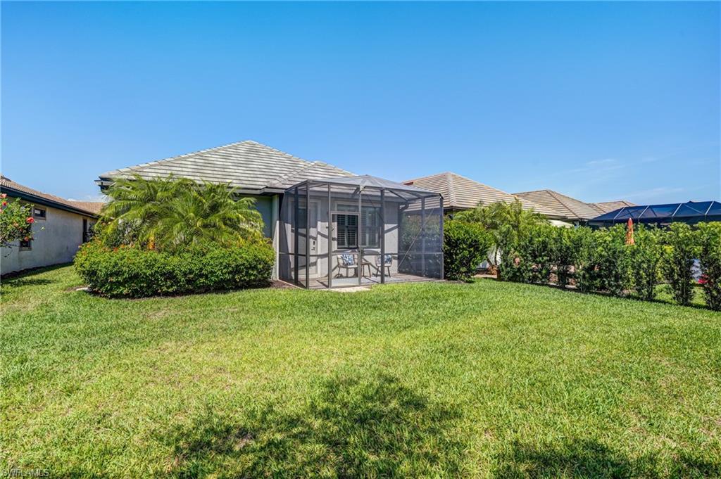 20308 Corkscrew Shores Boulevard Estero, FL 33928 - Photo 28 of 47 View of green lawn featuring glass enclosure and a patio