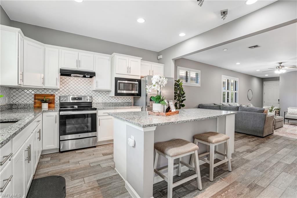 20308 Corkscrew Shores Boulevard Estero, FL 33928 - Photo 8 of 47 Kitchen with stainless steel appliances, recessed lighting, backsplash, light wood-style floors, and white cabinetry