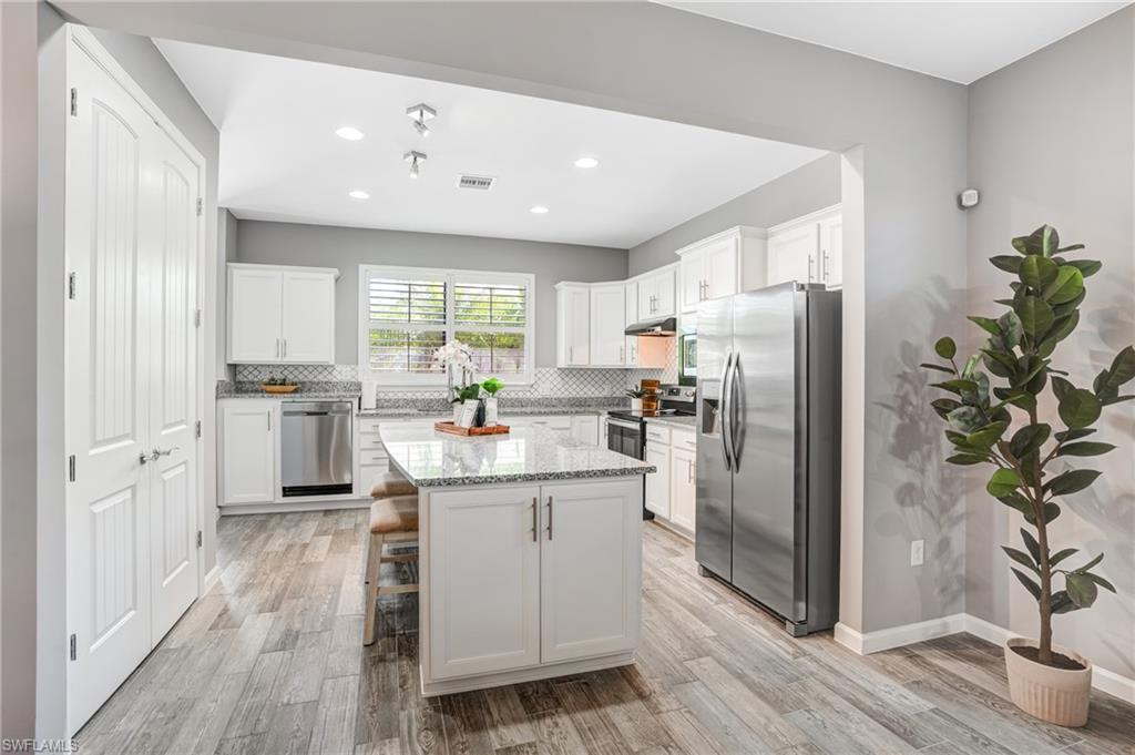 20308 Corkscrew Shores Boulevard Estero, FL 33928 - Photo 9 of 47 Kitchen with appliances with stainless steel finishes, tasteful backsplash, under cabinet range hood, light wood finished floors, and recessed lighting