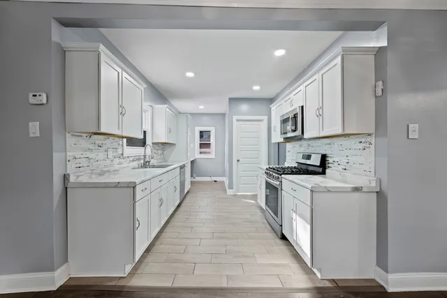 a large kitchen with stainless steel appliances granite countertop a lot of counter space and wooden floors