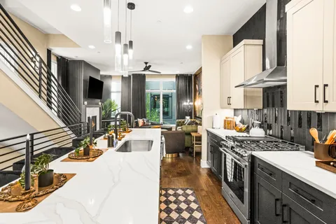 a kitchen with stainless steel appliances kitchen island granite countertop a stove a sink dishwasher and white cabinets with wooden floor