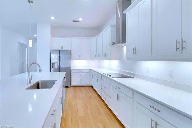 a large kitchen with stainless steel appliances granite countertop a sink a stove and white cabinets