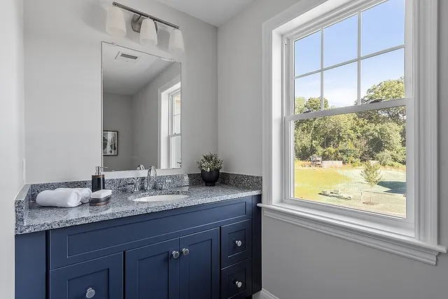 a bathroom with a granite countertop sink mirror and window