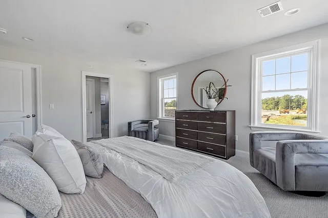 a bedroom with a bed a dresser and a large window
