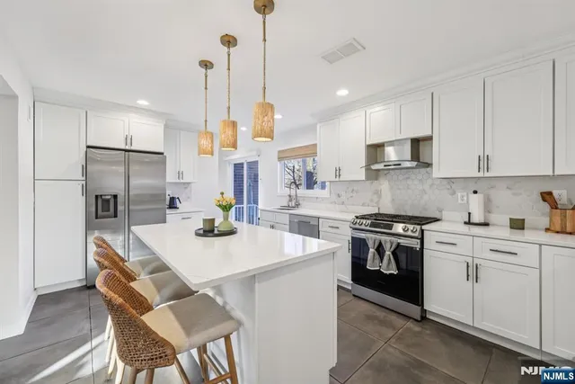 a kitchen with stainless steel appliances kitchen island granite countertop a stove a sink a refrigerator a center island and cabinets