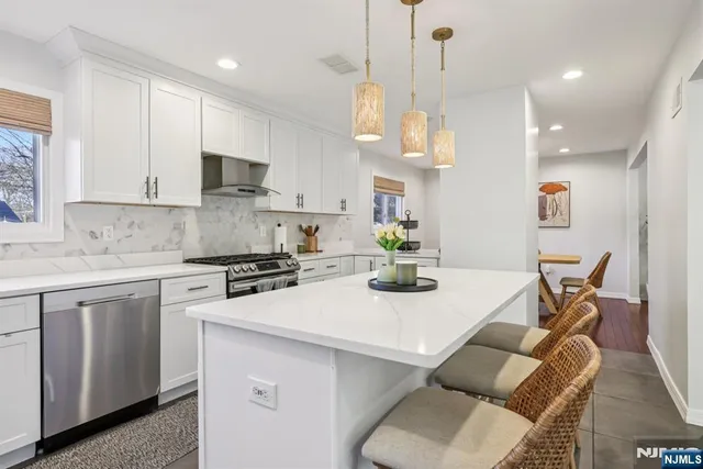 a kitchen with stainless steel appliances kitchen island granite countertop a sink a stove a dining table and chairs