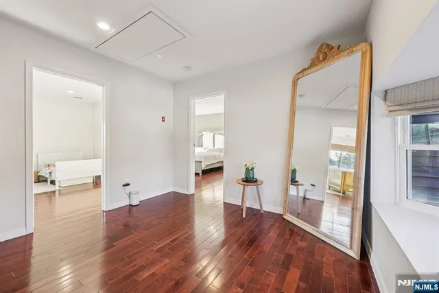 a view of a hallway view with wooden floor and a living room