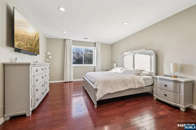 a spacious bedroom with a large bed and a flat tv screen on dresser