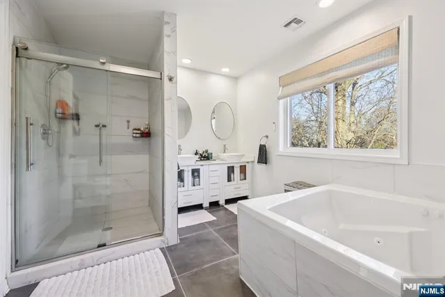 a bathroom with a bathtub shower sink mirror and toilet