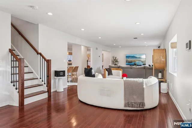 a living room with furniture and kitchen view with wooden floor